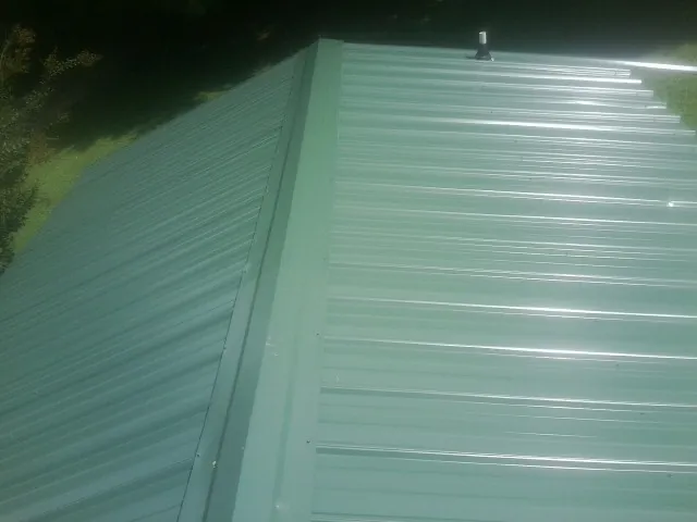 New green metal panels meeting at the ridge of a roof — Flat Roof Repair work by our crew in Rosebud