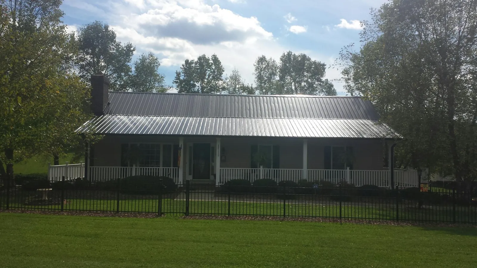 Gray metal roof on a brick ranch with a full width front porch — Gutter Guard Installation work by our crew in Rosebud
