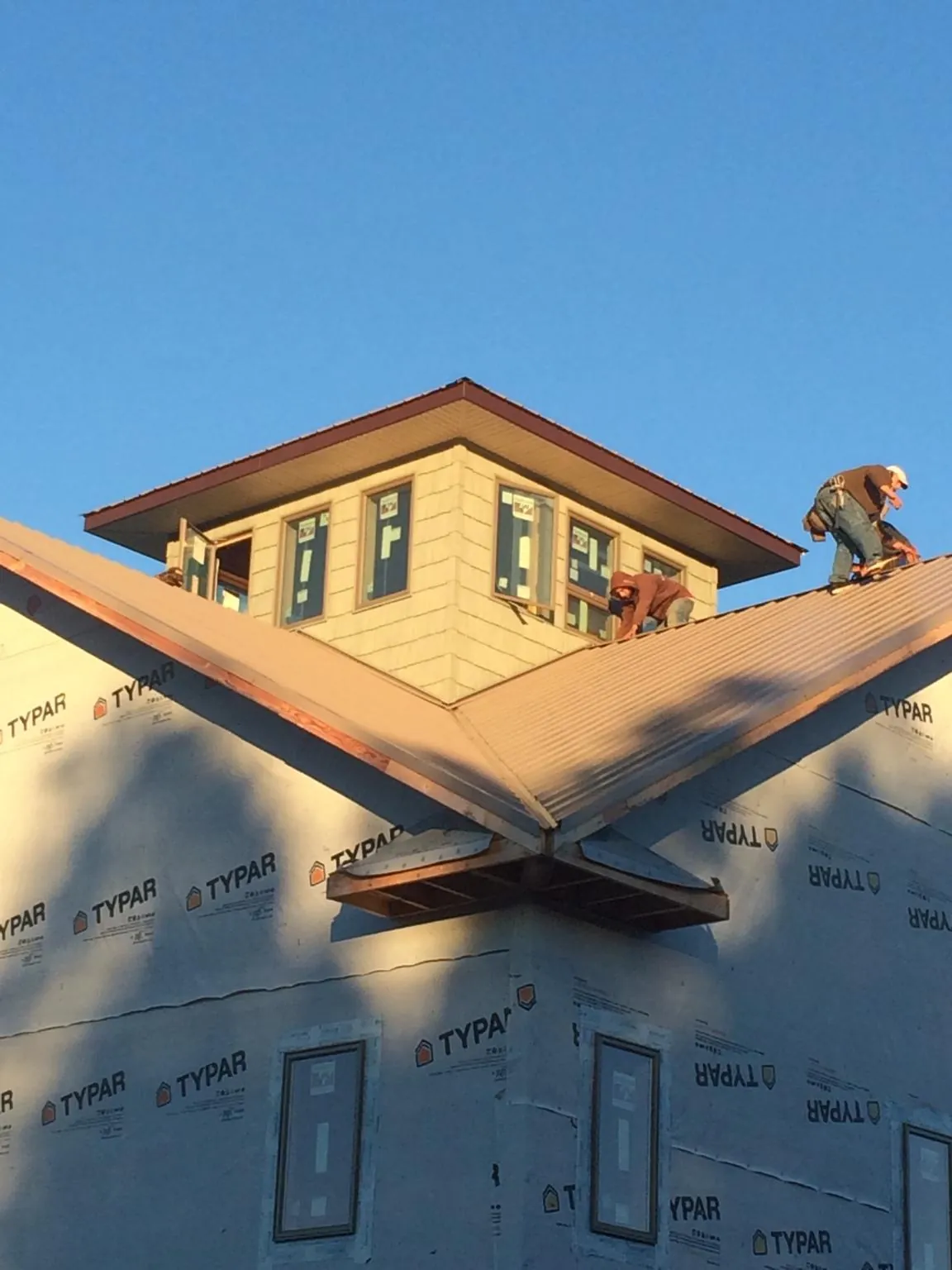 Roofers working around a rooftop cupola on a new metal roof at sunset — Roof Waterproofing in Rosebud by Roofing Brothers
